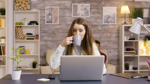 Young woman using laptop while sitting on table