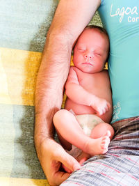 Midsection of father with sleeping baby on bed