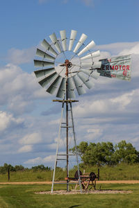 Low angle view of windmill on field against sky