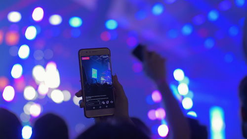 Low angle view of hand using smart phone at night