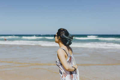 Woman at beach against clear sky
