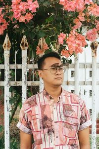 Portrait of young man standing by flowering plants