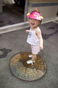 High angle view of cute girl standing on manhole
