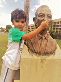 Portrait of boy holding statue nose in city