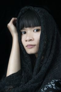 Close-up portrait of young woman against black background