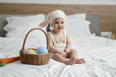 Cute baby girl by basket on bed