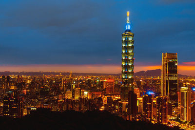 Illuminated buildings in city against sky at night