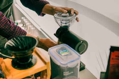 A barista grinding coffee beans with a grinder in a coffee shop in the morning