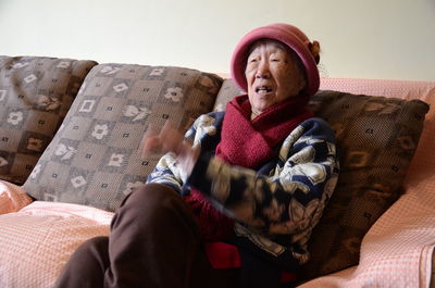 Blurred motion of senior woman sitting on sofa