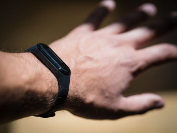 Close-up of human hand and fitness band against blurred background