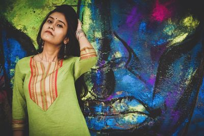 Full length of woman standing against graffiti wall