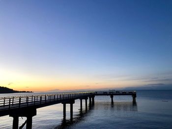 Pier over sea against sky during sunset