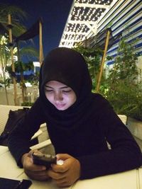 Portrait of smiling young woman holding ice cream sitting outdoors