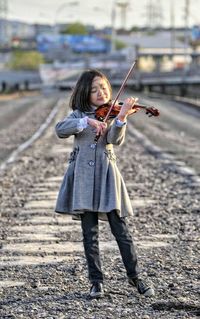 Full length of girl playing violin while standing outdoors