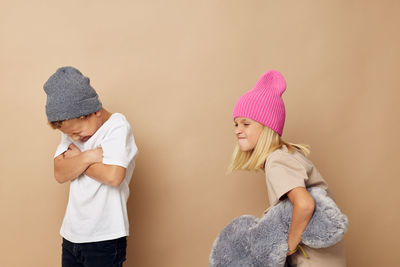 Sibling fighting against beige background