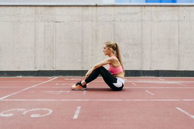 Full length side view of man sitting on wall