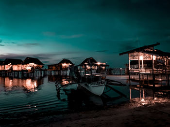 Stilt houses by sea against sky at dusk