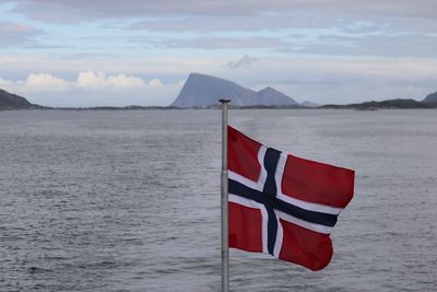 Scenic view of norway flag on sea against sky 