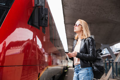 Portrait of young woman standing against train