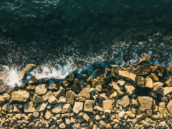 Aerial top view of sea waves hitting rocks on the beach