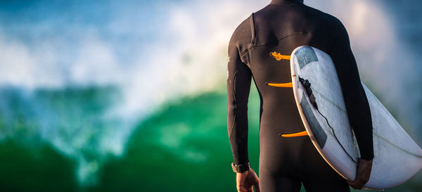 Rear view of man with surfboard