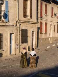 Rear view of people walking on street amidst buildings