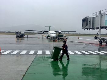 Men standing on airport runway against sky during rainy season
