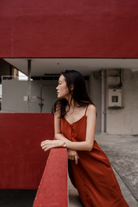 Young woman sitting on red umbrella
