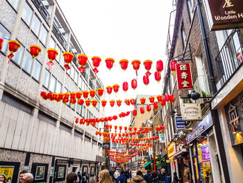 Low angle view of lanterns hanging in city against sky