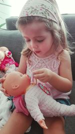 Close-up of cute baby girl sitting on sofa