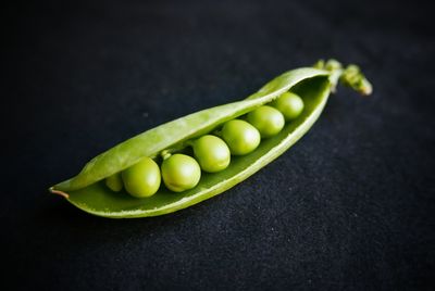 Close-up of open pea pods against black background