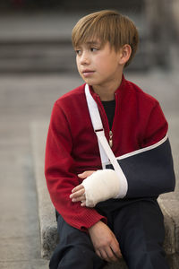 Smiling boy with orthopedic cast sitting outdoors