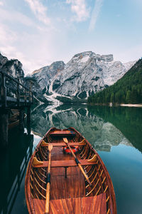 Boat moored at lake against mountains during winter