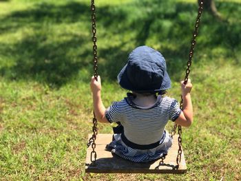 Rear view of girl sitting on swing at playground