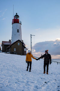 People on snow covered land against sky