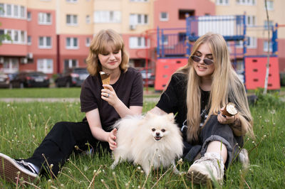 Two funny girls are eating ice cream and playing with a pomeranian dog. holidays