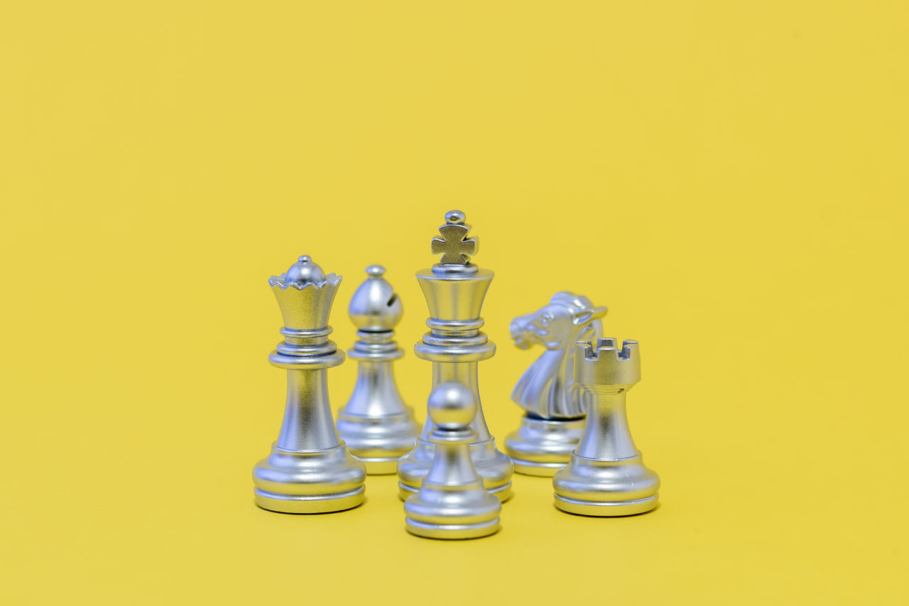 LOW ANGLE VIEW OF CHESS PIECES ON YELLOW BACKGROUND