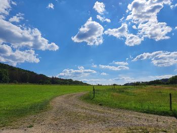 Scenic view of road amidst field against sky