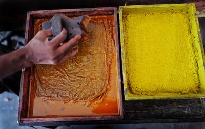 Cropped hand of man with paint in container