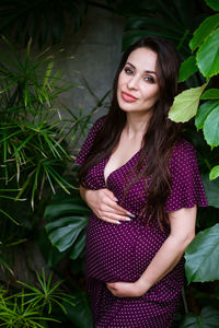 Beautiful pregnant woman feels great in beautiful dress with long flowing hair