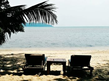 Chair on beach against clear sky