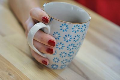 Midsection of woman holding coffee cup on table