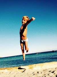 Full length of woman walking on beach against clear sky