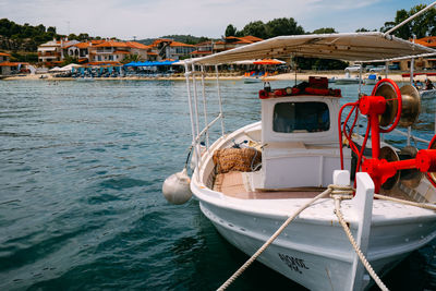 Fishing boats in greece, white small boats and blue sea close up