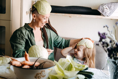 Happy vegan family mom and baby daughter cooking together and having fun on kitchen. family cooking