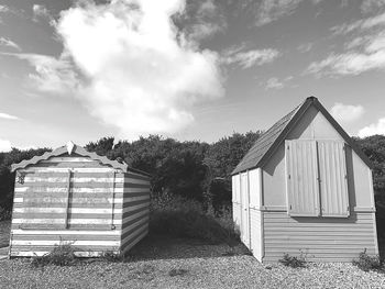 Barn on field by building against sky