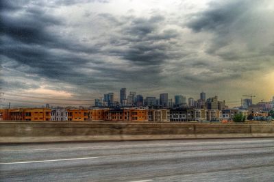 Buildings in city against cloudy sky