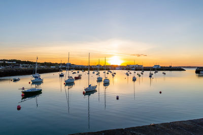 Boats moored in harbor at sunset