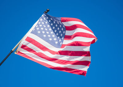 Low angle view of american flag against clear blue sky