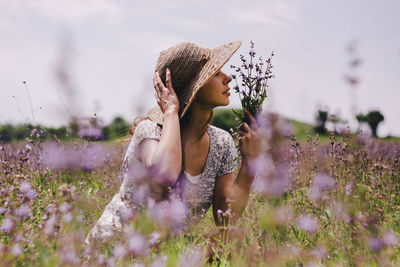 Woman smelling flowers on field
